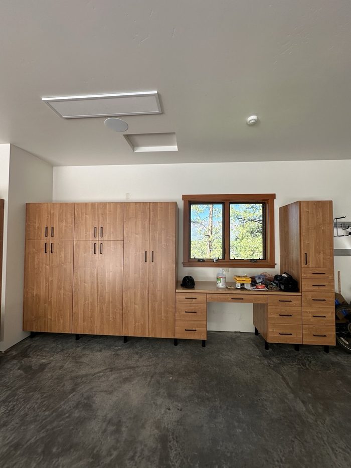 Garage wall of wood-grain cabinets with a built-in workbench under a window