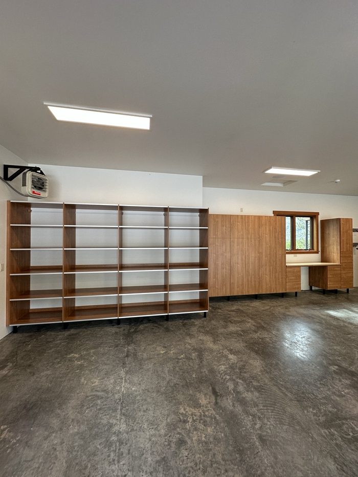 Garage with open shelving units beside tall wood-grain cabinets